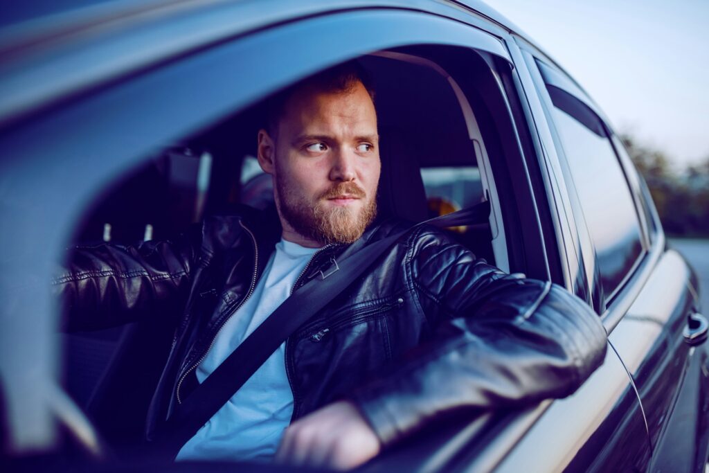 Driver looking concerned while sitting in his car, highlighting the importance of addressing strange brake noises for safety.